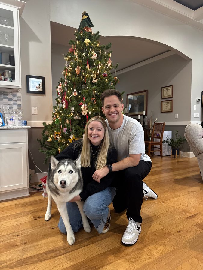 Dr. Little with his wife, Hannah, and their husky, Shadow, in front of a Christmas tree