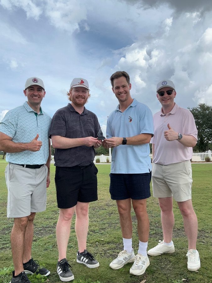 Dr. Little holding a trophy with friends after a golf tournament win