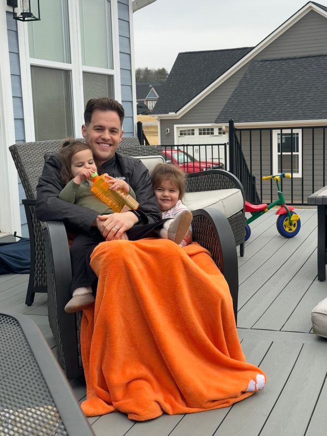 Dr. Little relaxing on a deck holding his two young nieces